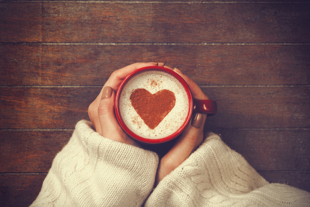 woman holding hot cup of coffee, with heart shape woman holding hot cup of coffee, with heart shape